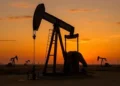 An oil pump jack operating at sunset representing global crude oil production and commodity trading