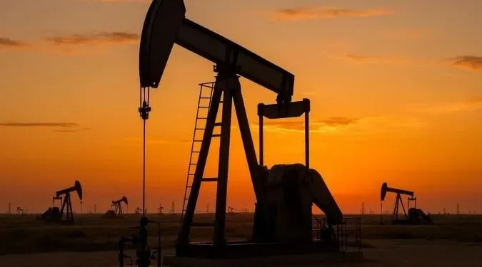 An oil pump jack operating at sunset representing global crude oil production and commodity trading