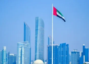 UAE flag waving in Abu Dhabi skyline under a clear sky.