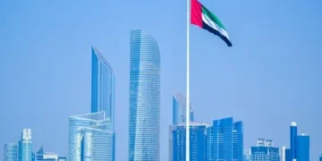 UAE flag waving in Abu Dhabi skyline under a clear sky.