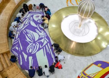 Healthcare workers at Burjeel Medical City standing around a 250-square-meter floral carpet featuring UAE President Sheikh Mohamed bin Zayed Al Nahyan.