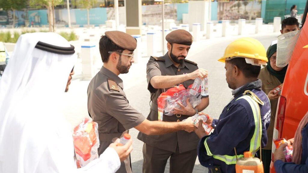GDRFA officers distributing cold drinking water and refreshments to outdoor workers in Dubai during summer.