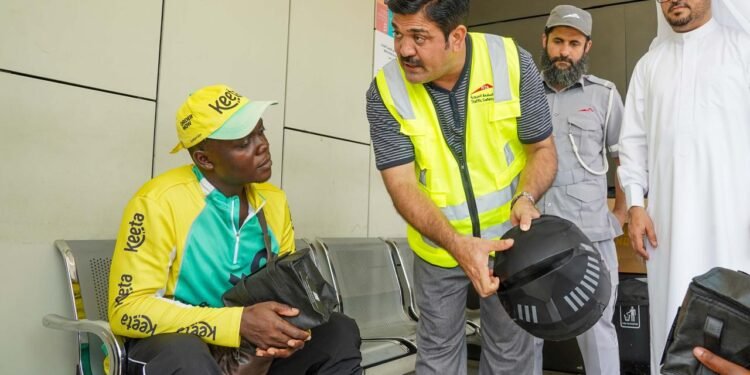 Dubai RTA official distributing health kit to motorcycle delivery rider during summer safety drive