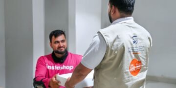 Delivery riders receiving meals at a Dubai metro station rest area during the summer midday break.